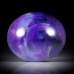 Sugilith mit Richterit 58.12ct. ovaler Cabochon ca.31x26x10mm